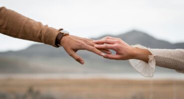 Jeweils eine Hand von Mann und Frau berühren sich an den Fingerspitzen.